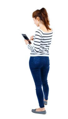 arkadan görünüşü mobil bir fon kullanan duran genç güzel kadın