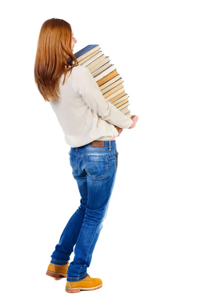 Mädchen trägt einen schweren Stapel Bücher. Ansicht von hinten. — Stockfoto