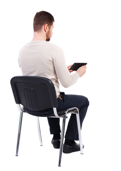 Back view of man sitting on chair and looks at the screen – stockfoto