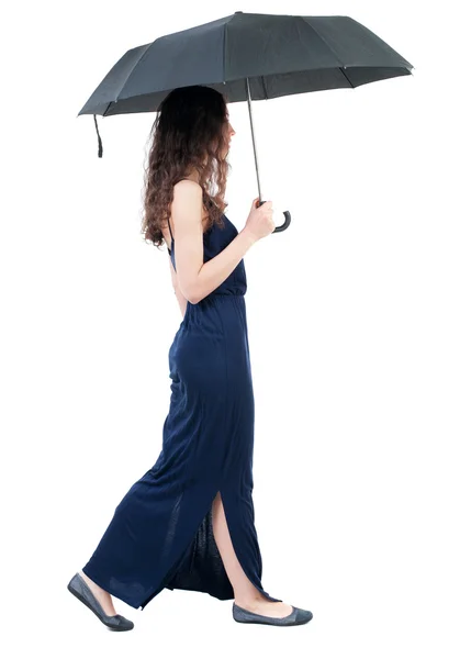 Jovem mulher de vestido andando sob um guarda-chuva. — Fotografia de Stock