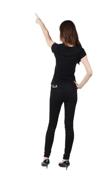 Back view of young brunette woman pointing at wall . — Stock Photo, Image