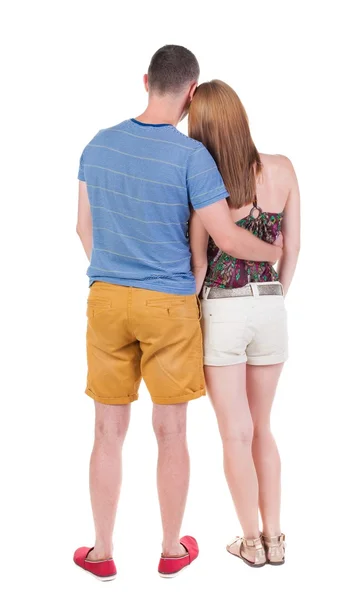 Vista posterior de joven abrazando par en pantalones cortos abrazo y mira. — Foto de Stock