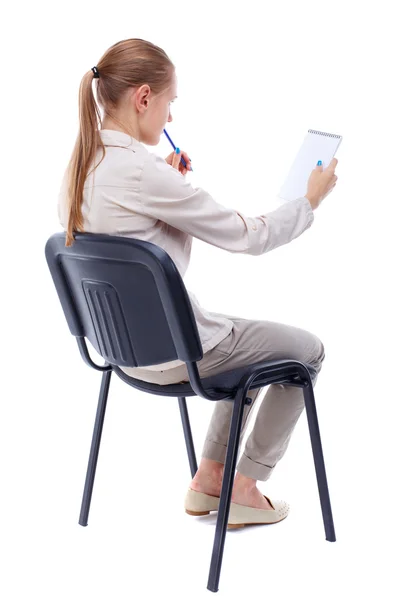 Back view of young beautiful  woman sitting on chair and  takes — Fotografia de Stock