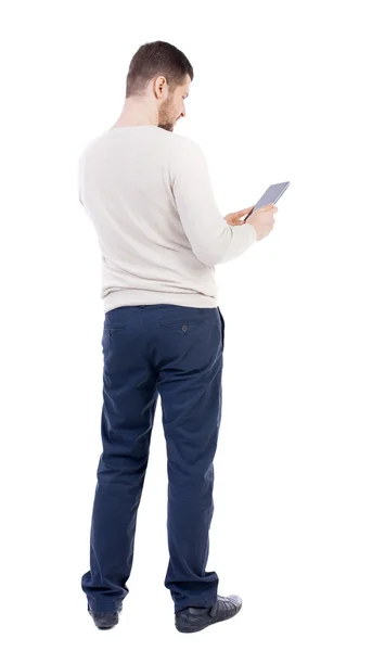 Achteraanzicht van permanent jongeman met tablet pc in de hand — Stockfoto