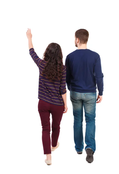 Back view of walking young couple man and woman pointing. — Stock Photo, Image