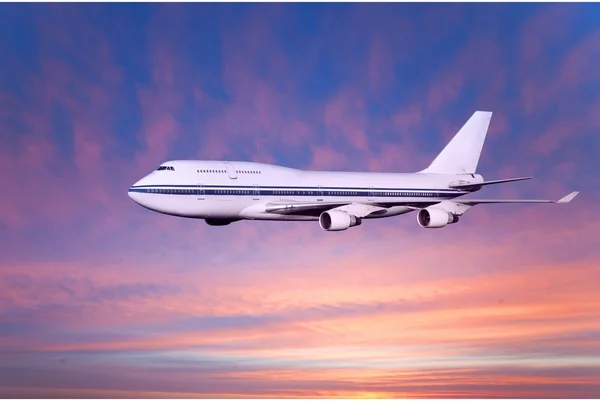 Avião de passageiros nas nuvens ao pôr do sol — Fotografia de Stock