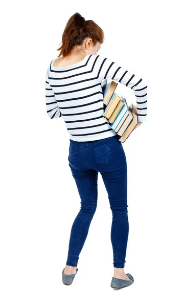 Meisje draagt een zware stapel boeken. Achteraanzicht. — Stockfoto