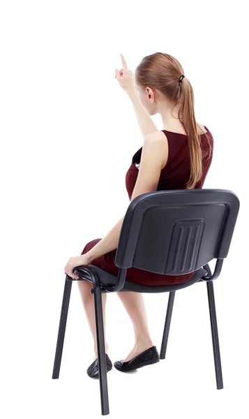 Achteraanzicht van jonge mooie vrouw zittend op een stoel en pointin — Stockfoto