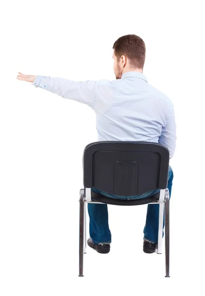 Vista posterior de hombre de negocios joven sentado en silla y señalando — Foto de Stock