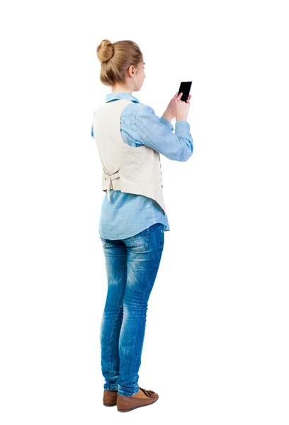 Back view of standing young beautiful  woman  in vest and using — Stock Photo, Image