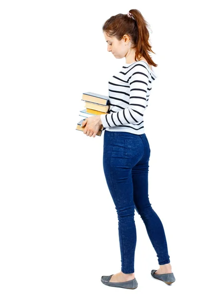 Mädchen trägt einen schweren Stapel Bücher. Ansicht von hinten. — Stockfoto