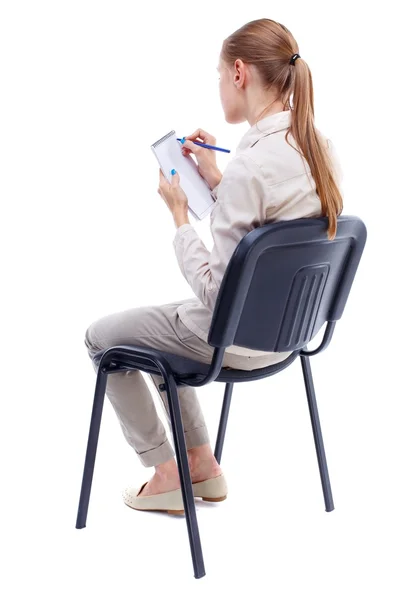 Back view of young beautiful  woman sitting on chair and  takes — 스톡 사진