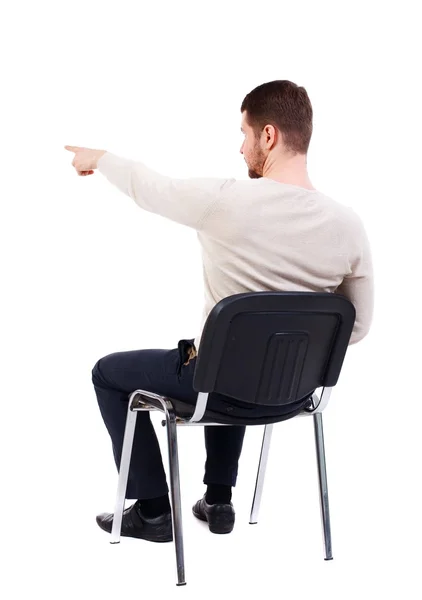 Vista posterior de hombre de negocios joven sentado en silla y señalando — Foto de Stock