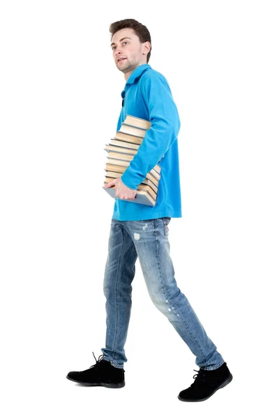 Kitapların bir yığınına gidiyor adam yan görünüm taşır. — Stok fotoğraf