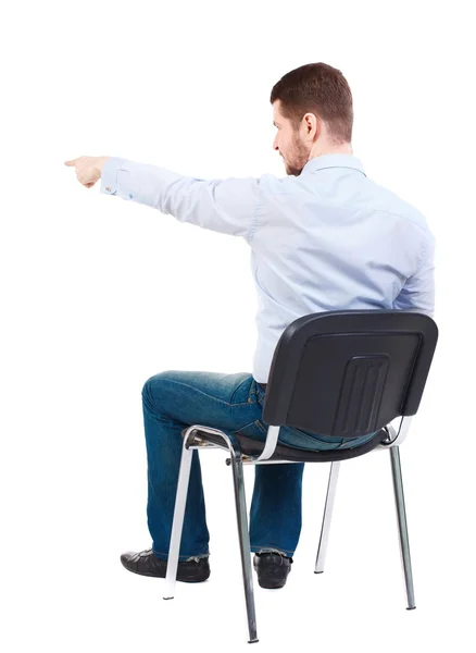Widok z młody biznes człowiek siedzi na fotelu i wskazując tyłu — Zdjęcie stockowe