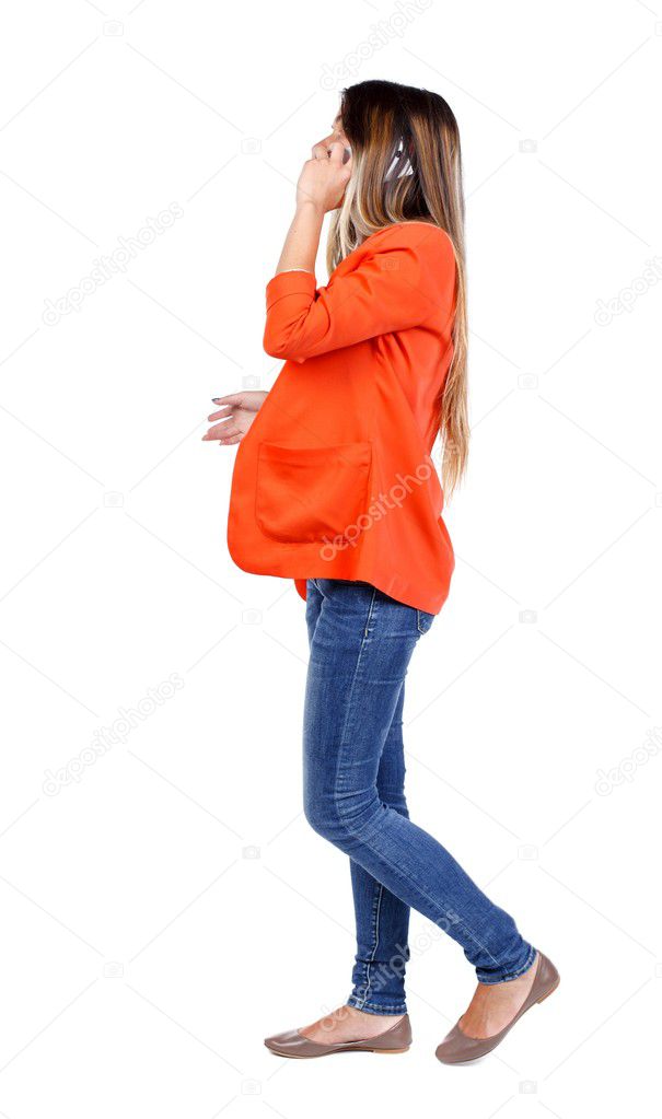 side view of a woman walking with mobile phone.