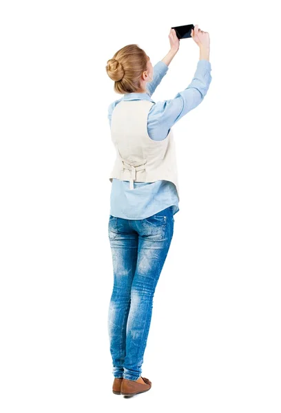 Back view of standing young beautiful  woman  in vest and using — Stock Photo, Image