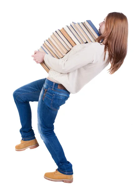 Uma garota carrega uma pesado pilha de livros. vista traseira. vista traseira pesso — Fotografia de Stock