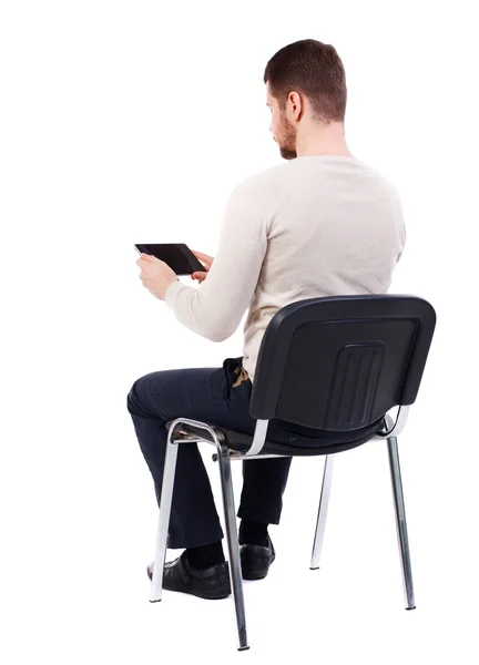 Back view of man sitting on chair and looks at the screen – stockfoto
