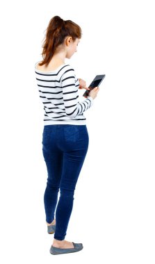 arkadan görünüşü mobil bir fon kullanan duran genç güzel kadın