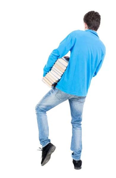 Un hombre lleva un pesado montón de libros. Vista posterior. — Foto de Stock