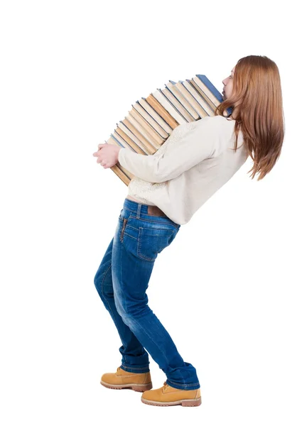 Uma garota carrega uma pesado pilha de livros. vista traseira. vista traseira pesso — Fotografia de Stock