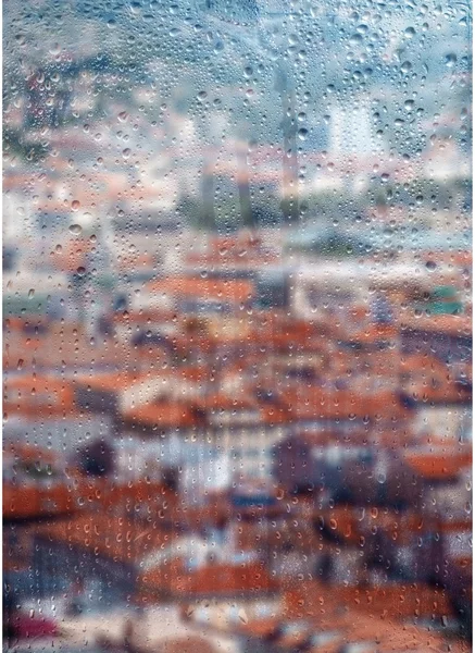 Herbst, verregnete Stadt durch ein Fenster mit Regentropfen. lizenzfreie Stockfotos