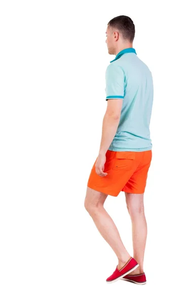 Hintere Ansicht gehen gut aussehender Mann in kurzen Hosen. Walking jungen Kerl — Stockfoto