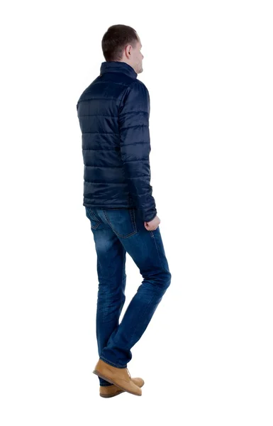 Bakifrån gå stilig man i jeans och jacka. — Stockfoto