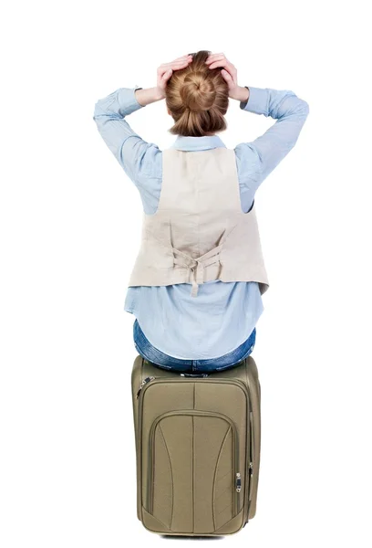 Vista traseira da mulher chocada no colete senta-se em uma mala. — Fotografia de Stock