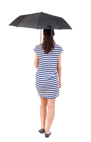 Jovem mulher de vestido andando sob um guarda-chuva. — Fotografia de Stock