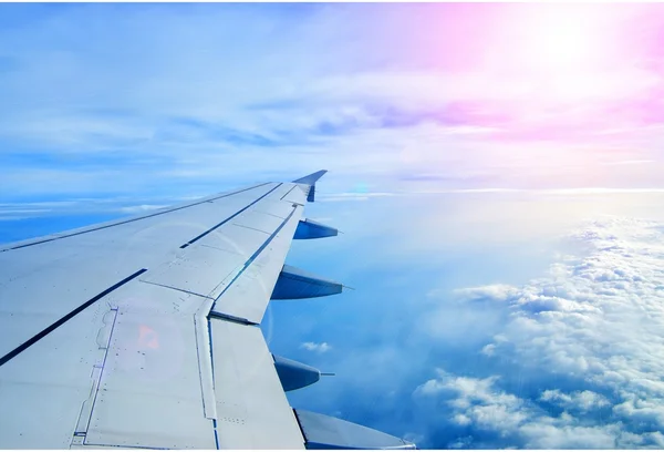 Aile d'un avion volant au-dessus des nuages Image En Vente