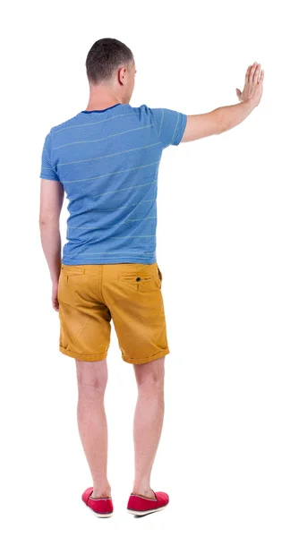 Bakifrån av människan. ung man i shorts pressar ner på något — Stockfoto