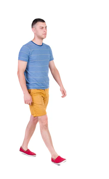 Hintere Ansicht gehen gut aussehender Mann in kurzen Hosen. Walking jungen Kerl — Stockfoto