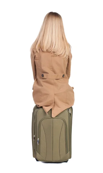 Achteraanzicht van vrouw in mantel zit op koffer. — Stockfoto