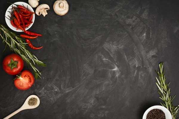 Black table with food ingredients and utensil — Stock Photo, Image