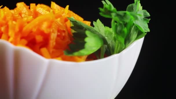 Морковный салат вращается в черной миске — стоковое видео