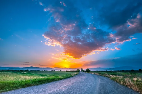 Estrada no prado com belo céu por do sol — Fotografia de Stock