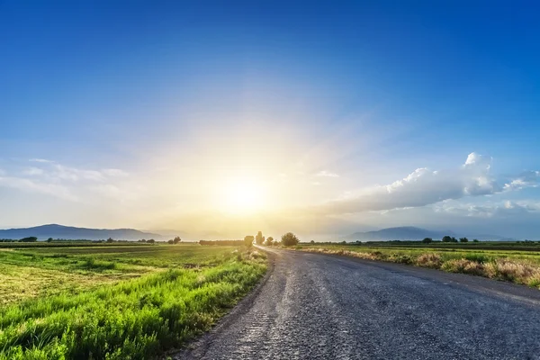 Estrada no prado com belo céu por do sol — Fotografia de Stock