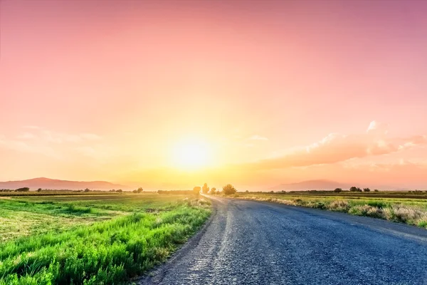 Estrada no prado com belo céu por do sol — Fotografia de Stock