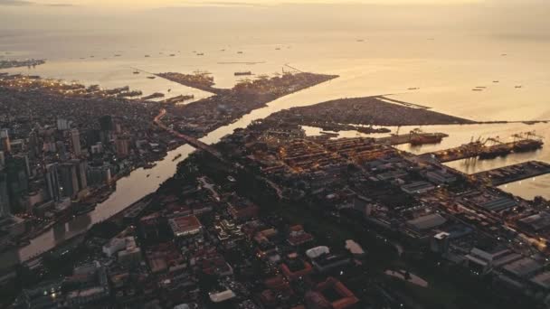 Zonsondergang aan de baai van de oceaan met stad aan de rivieroevers antenne. Verlicht stadsgezicht met straten en wegen — Stockvideo