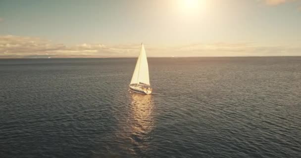 Aéreo de iate cruzeiro em águas oceânicas ao sol. Veleiro branco em mar aberto. Capa marinha serena — Vídeo de Stock