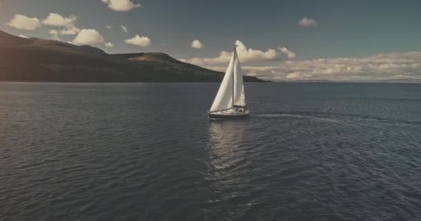 Barco à vela na costa do oceano de montanha aérea. Velas de iate com belas nuvens fofas céu em mar aberto — Vídeo de Stock