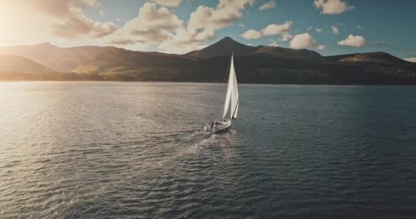 Yacht in bright sunlight sailing at open sea bay aerial. Luxury sailboat cruise at Brodick Pier — Stock Video