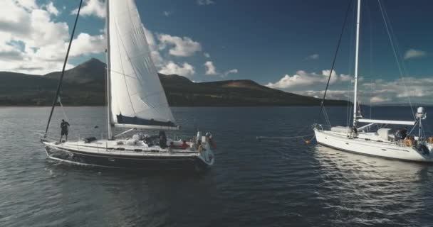 Primer plano aéreo de yates que navegan en el paisaje marino de la costa de la bahía del océano de la isla de montaña de Arran, Escocia — Vídeo de stock