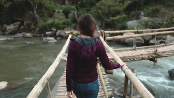 Çekici bir kadın, nehir köprüsü, Tayland yağmur ormanları. Taş sahildeki su manzarasına bakan bir kız. — Stok video