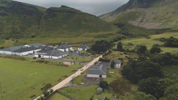 아란 위스키 증류 공장의 에어 버스입니다. 녹색 산 계곡의 도로입니다. 집들과 수용소가 있는 스코틀랜드 마을 — 비디오