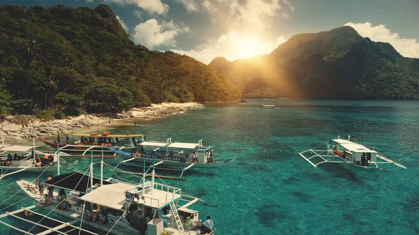 Zon boven bergketens, groen tropisch bos aan de baai van de oceaan. Mensen rusten op zandstrand, Filippijnen — Stockfoto