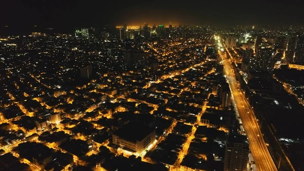 Calles nocturnas iluminadas en la antena de Manila. Edificios modernos, rascacielos, autopista en el paisaje urbano — Foto de Stock