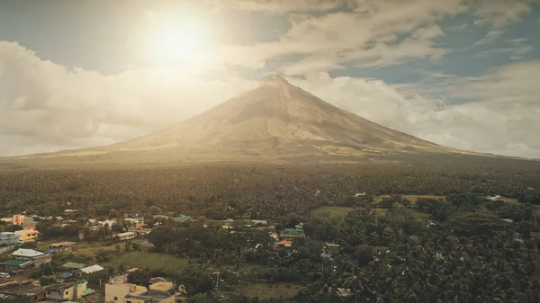 Vulcano aereo eruttare alla luce del sole primo piano. Cityscape del sole della città rurale alla valle verde del vulcano — Foto Stock